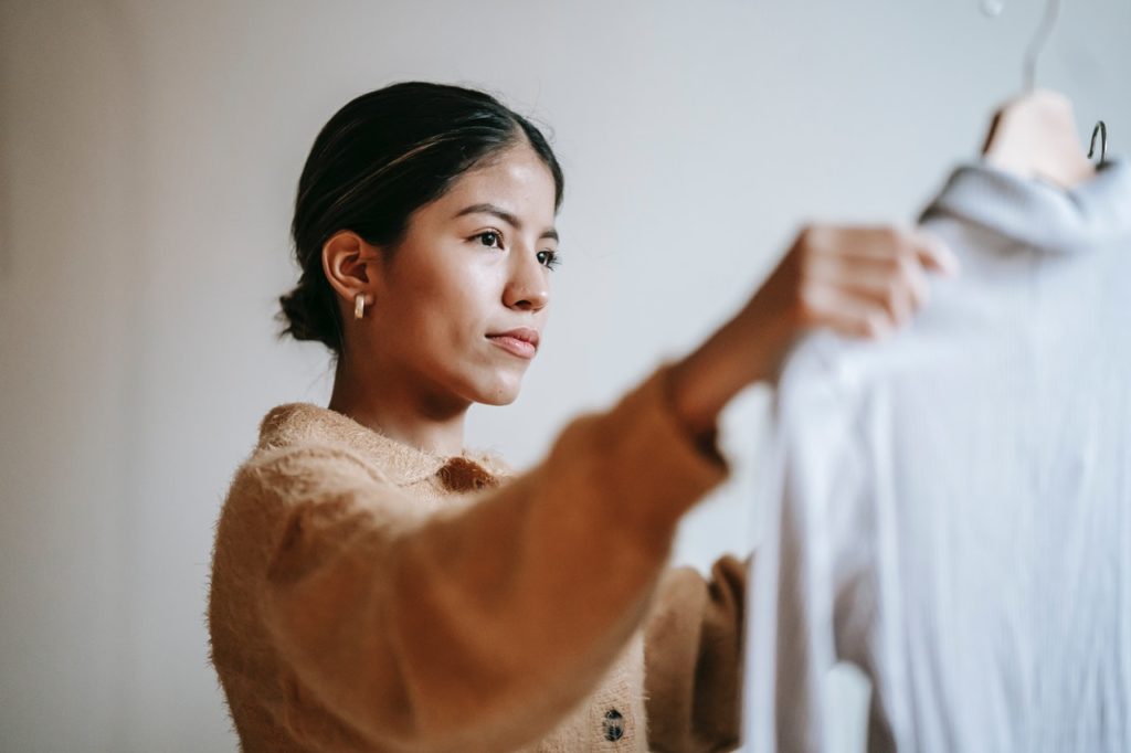 A woman holds up and examines a shirt.
