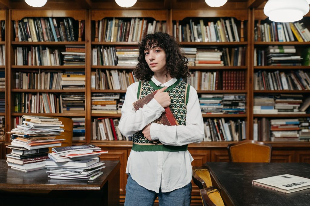 A person holds a book to their chest in a library.